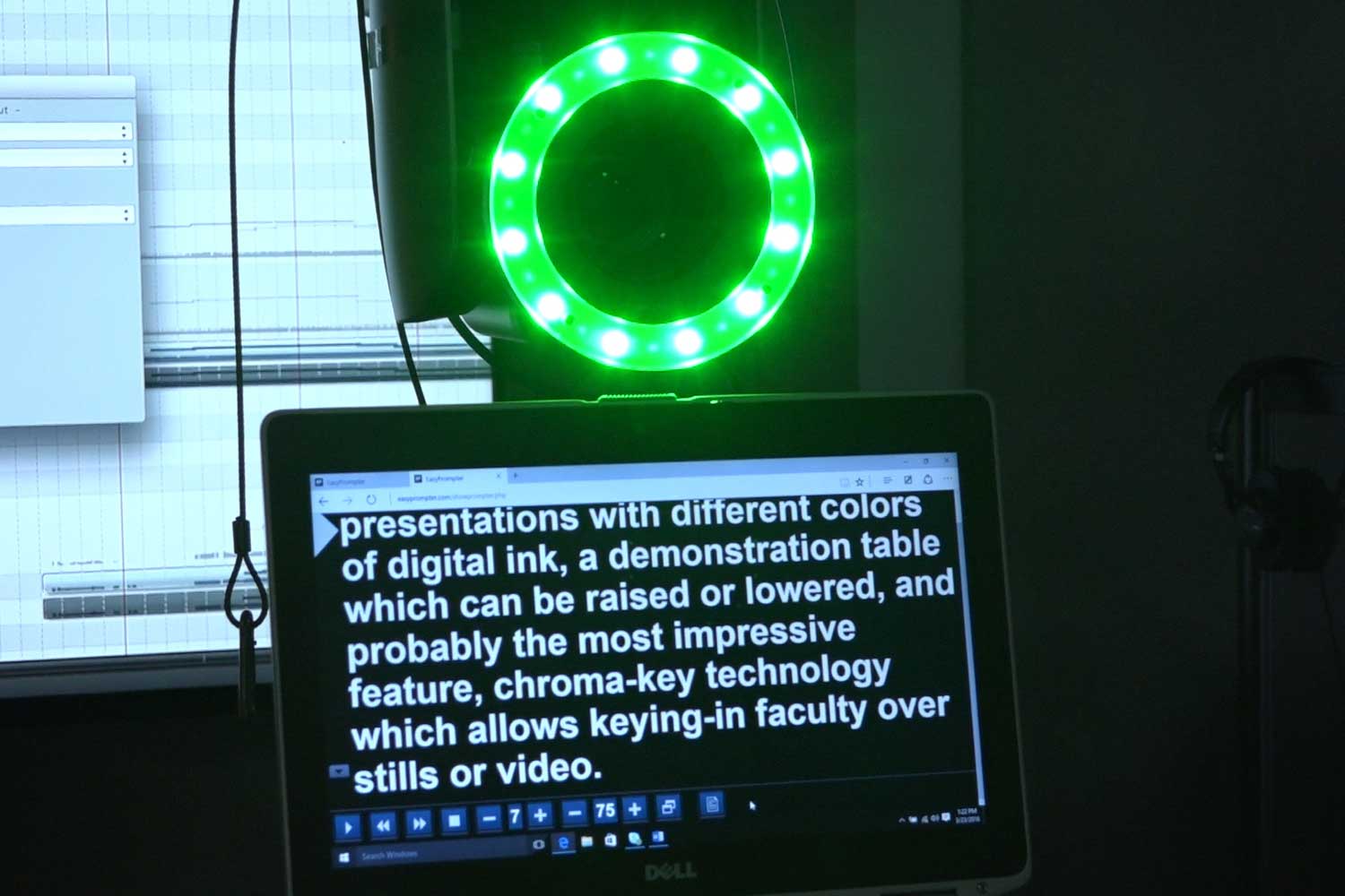 A teleprompter displaying text to be read in a studio, with a ring light and camera next to the teleprompter.